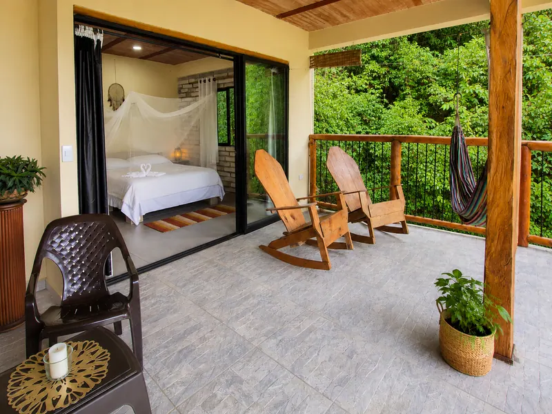 Terrace with a hammock and wooden rocking chairs, with glass doors open to the bedroom