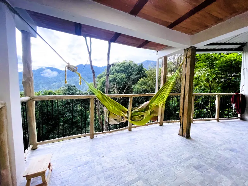 Covered terrace with a green hammock and mountain views